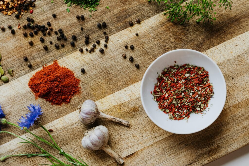 A rustic flat lay of various spices and herbs on a wooden surface.